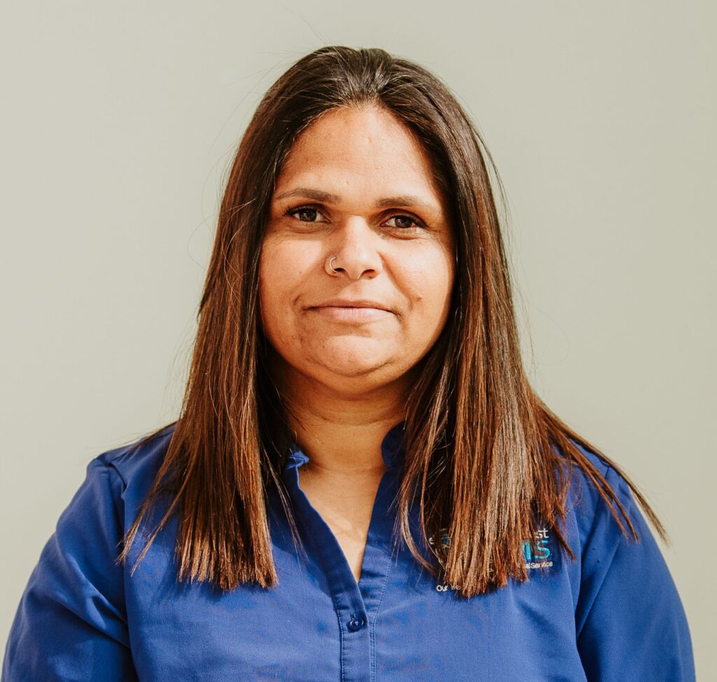 Woman looking at the camera. She is wearing a uniform with a logo that is obscured by her long straight brown hair.